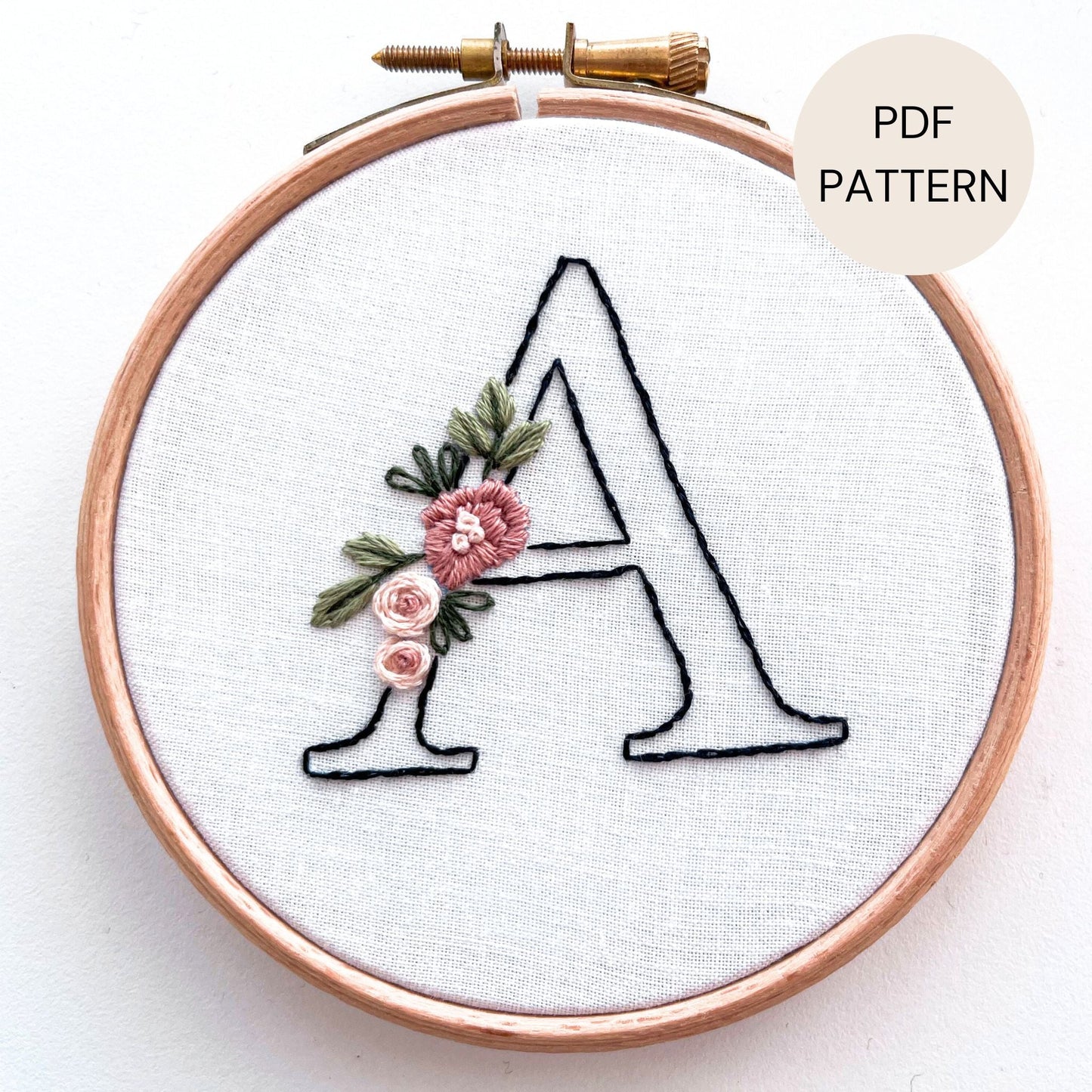 hand embroidery pattern with the letter A stitched in black outline decorated with pink flowers