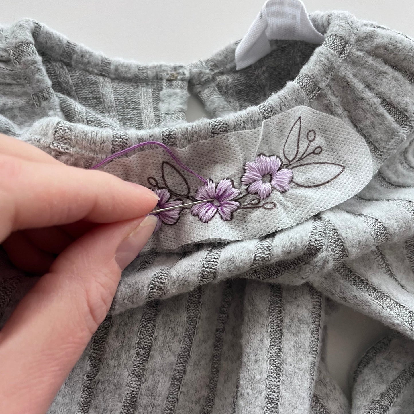 purple flower design being stitched onto child's clothes