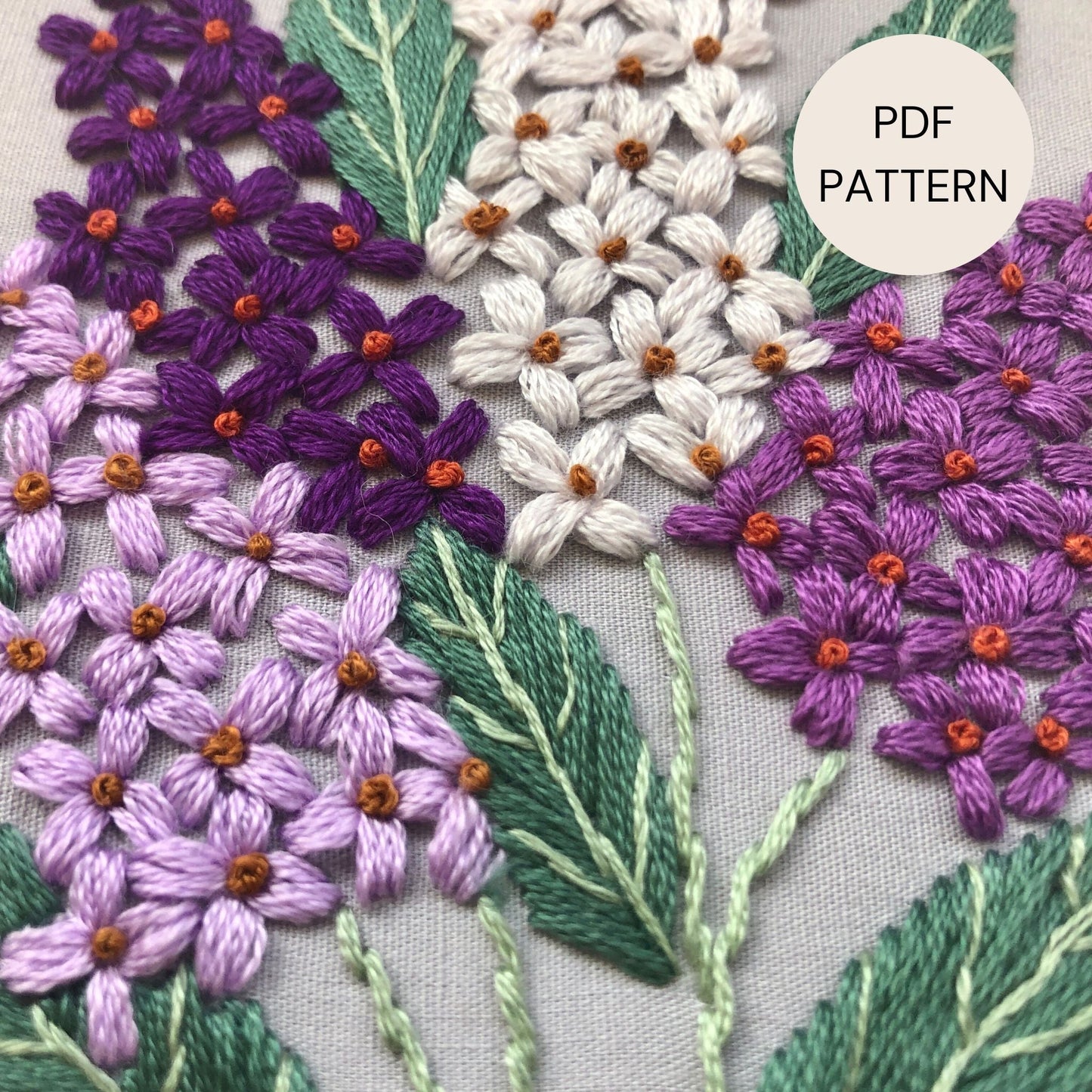 close up of purple, lavender and lilac coloured flowers hand stitched.